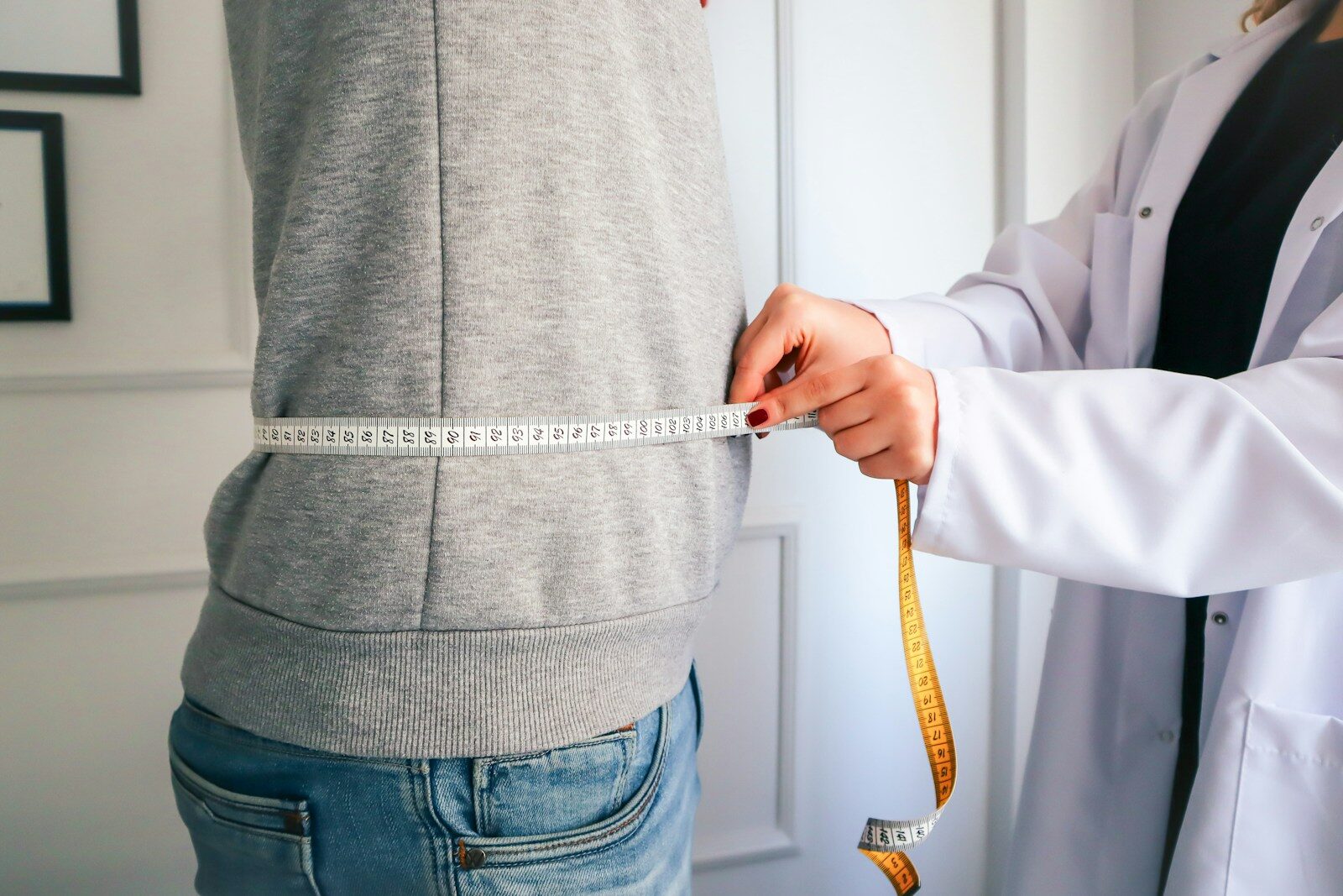 a woman measuring her waist with a measuring tape