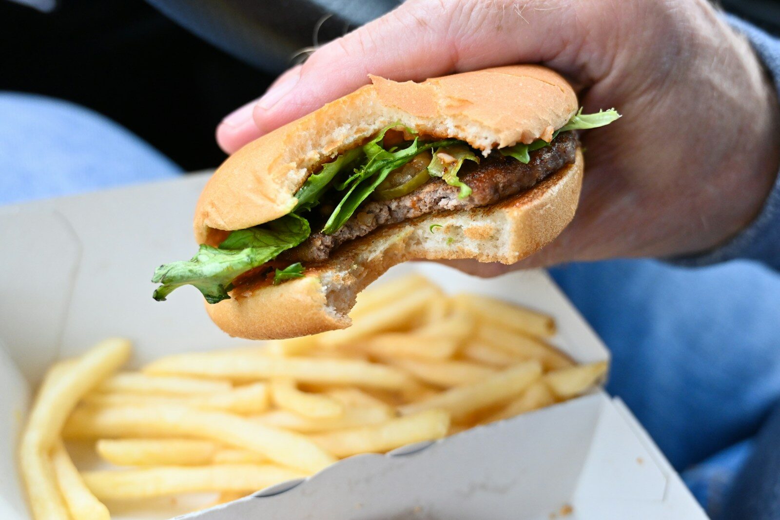 a person holding a sandwich and french fries